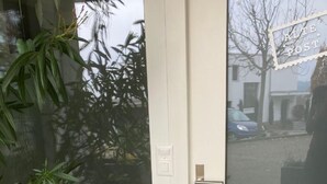 Cerca de madeira com diversas plantas e uma porta com painel de vidro.