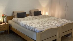 Quarto com cama de madeira, mesa de cabeceira com abajur e guarda-roupa.