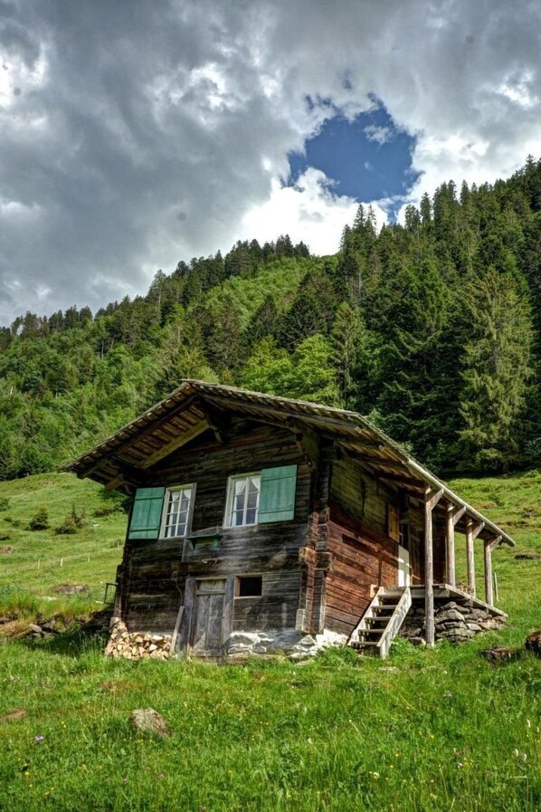 A rustic wooden cabin with a steep roof, a front porch, and a small staircase leading up to the entrance. - Kirschbaumhütte by Interhome (Gündlischwand)