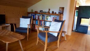 Un salon chaleureux avec un plancher en bois, deux fauteuils, une bibliothèque et une cheminée.