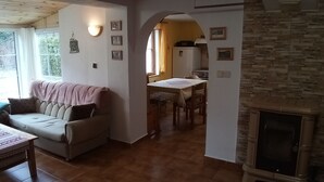 Een knusse woonkamer met een bank, een eettafel en een open haard.