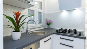 Eine moderne Küche mit Spüle aus Edelstahl, einem Gasherd und weißen Schränken.