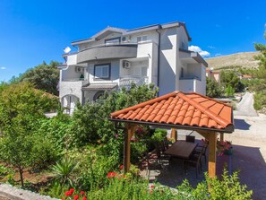Ein zweistöckiges Gebäude mit Garten-Terrasse und Sitzbereich im Freien.