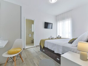 Ein modernes Hotelzimmer mit Bett, Schreibtisch, Stuhl und Fernseher.