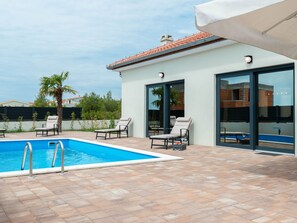 Ein moderner Poolbereich im Freien mit Liegestühlen und einem klaren, blauen Pool.