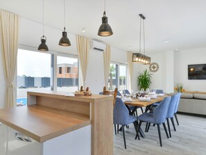 Ett modernt matområde med en köksö i trä, blå stolar och hängande lampor.