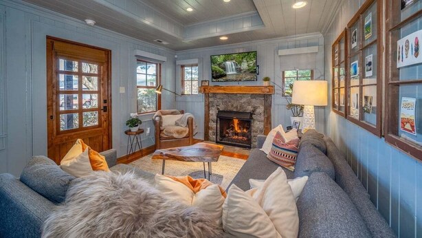 A cozy living room with a fireplace, comfortable seating, and a television. - Little Falls Bungalow (Brevard)