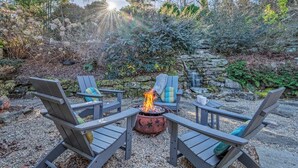 A fire pit surrounded by Adirondack chairs in a garden setting. - Little Falls Bungalow (Brevard)