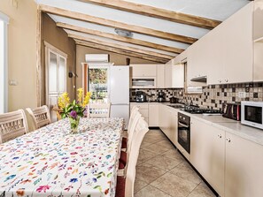 Una cocina con una mesa de comedor, sillas, un refrigerador, una estufa y un microondas.