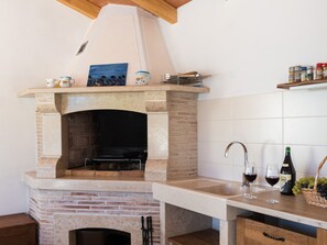 A kitchen with a built-in brick oven, a sink, and a wine bottle. - Apartment Oliva verde by Interhome (Trget)