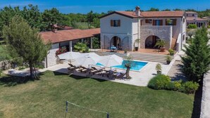Une maison à deux étages avec une piscine, un espace salon extérieur et un jardin.