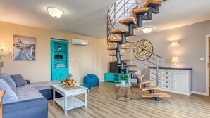 A modern living room with a spiral staircase, a large clock, and a teal cabinet. - Villa LETICIJA - Luxusvilla mit beheiztem Pool, Sauna, Fitness & Grillplatz in by Interhome (Hreljin)