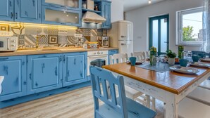 A kitchen with blue cabinets, a wooden countertop, and a dining area with a table and chairs. - Villa LETICIJA - Luxusvilla mit beheiztem Pool, Sauna, Fitness & Grillplatz in by Interhome (Hreljin)