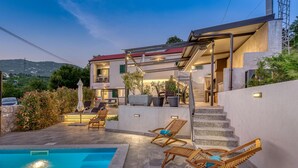 A two-story house with a swimming pool, outdoor seating, and a staircase leading to the upper floor. - Villa LETICIJA - Luxusvilla mit beheiztem Pool, Sauna, Fitness & Grillplatz in by Interhome (Hreljin)