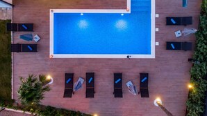 A rooftop swimming pool with a rectangular shape, surrounded by lounge chairs and umbrellas. - Schönes Haus für 8 Personen mit großem Schwimmbad by Interhome (Drazice)