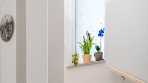 A wooden staircase with a small window above it, displaying potted plants and a blue orchid. - Schönes Haus für 8 Personen mit großem Schwimmbad by Interhome (Drazice)