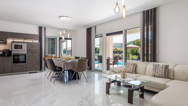 A modern living room with a glass coffee table, a sofa, and a dining area with a table set for four. - Schönes Haus für 8 Personen mit großem Schwimmbad by Interhome (Drazice)