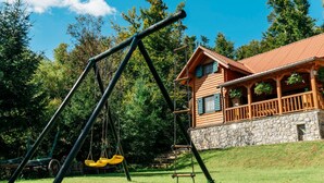 A wooden cabin with a stone foundation, a swing set, and a stone wall. - IDEAL FÜR FAMILIEN, PAARE UND NATURLIEBHABER by Interhome (Lokve)
