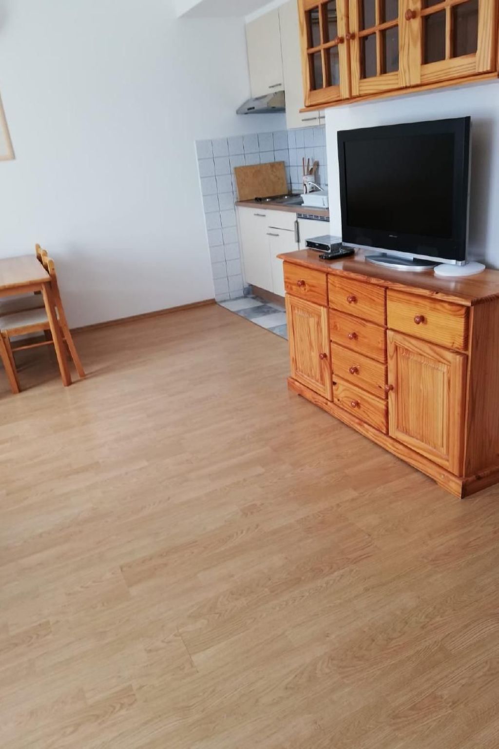 Eine Küche mit Holzschränken, einem Fernseher und einem Esstisch.