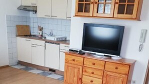 A kitchen with wooden cabinets, a built-in oven, and a television on a wooden stand. - Wohnung in Fazana mit Grill by Interhome (Fažana)
