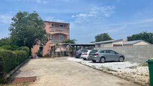 A residential area with a pink building, a covered parking area, and a concrete pathway. - Wohnung in Fazana mit Grill by Interhome (Fažana)