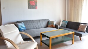 A modern living room with a grey sofa, a wooden coffee table, and a white armchair. - Gemütliche Wohnung in Meeresnähe by Interhome (Fažana)