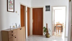 A hallway with wooden doors, a cabinet, a potted plant, and a dining area visible through an open door. - Gemütliche Wohnung in Meeresnähe by Interhome (Fažana)