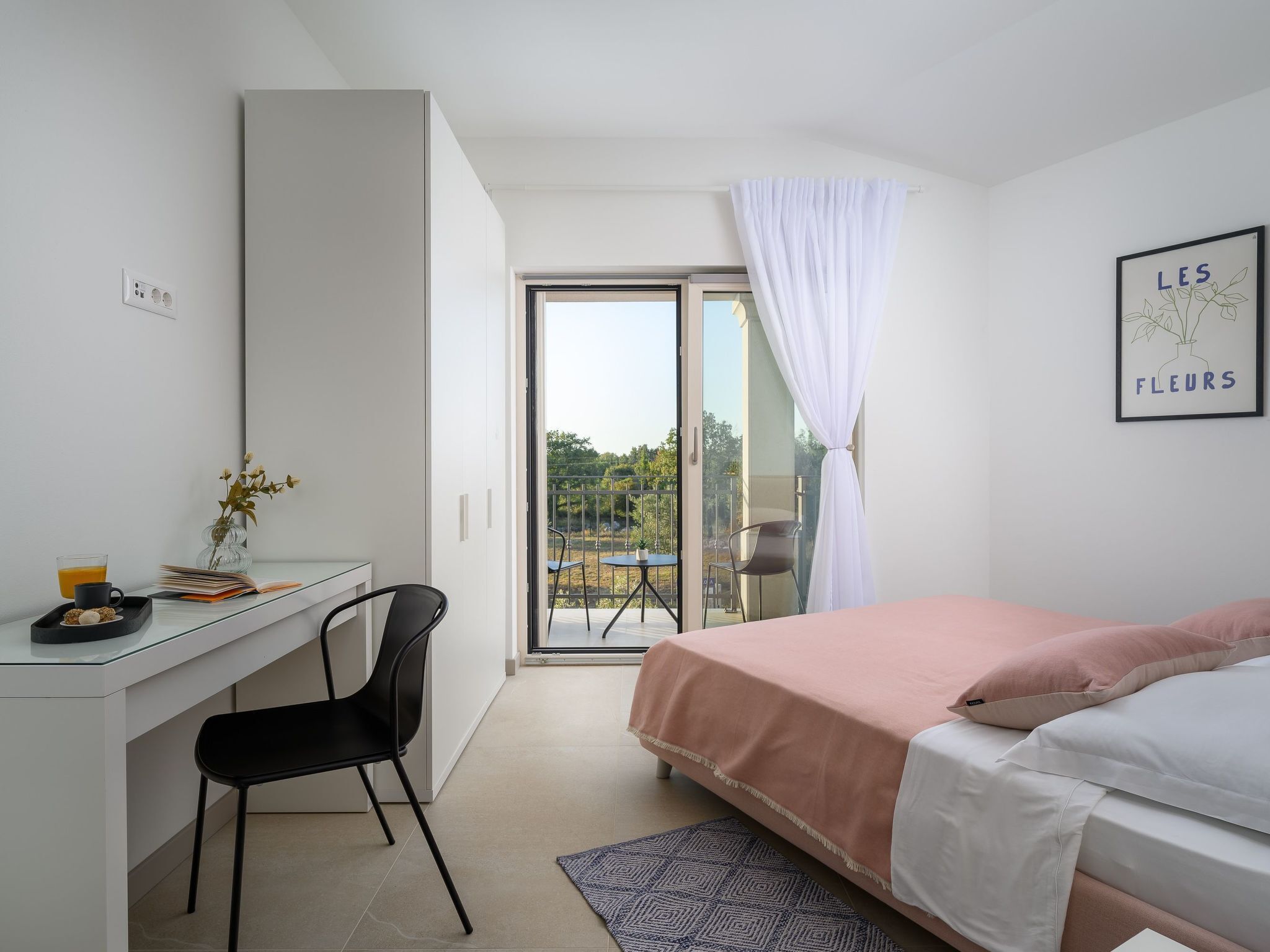 Une chambre moderne avec un bureau, un lit et un balcon offrant une vue agréable.