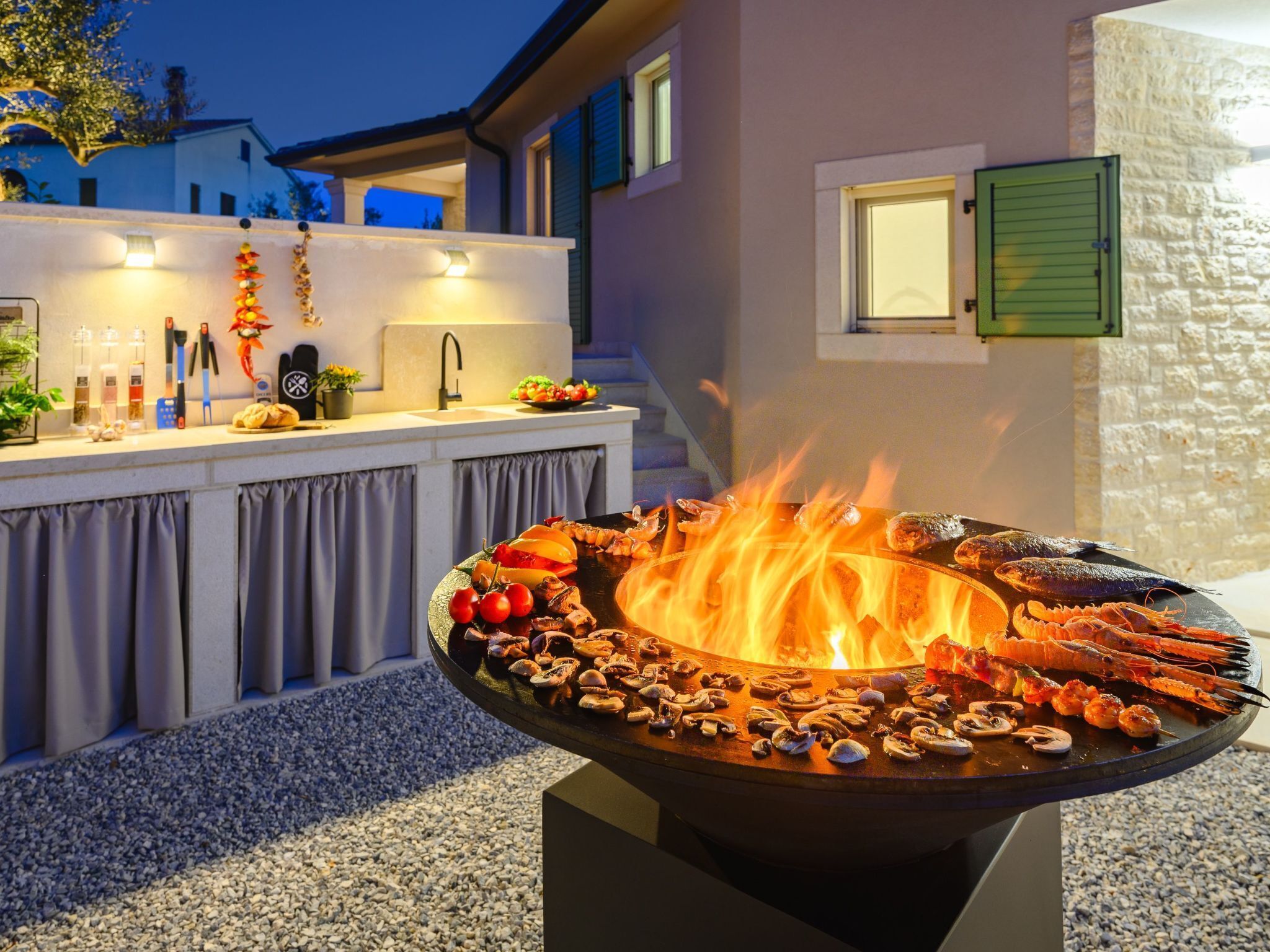 An outdoor bar area with a fire pit surrounded by seafood and vegetables.