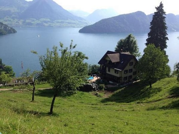 A house with a sloped roof, surrounded by a grassy area and a lake with mountains in the background. - Apartment Mätzli by Interhome (Vitznau)