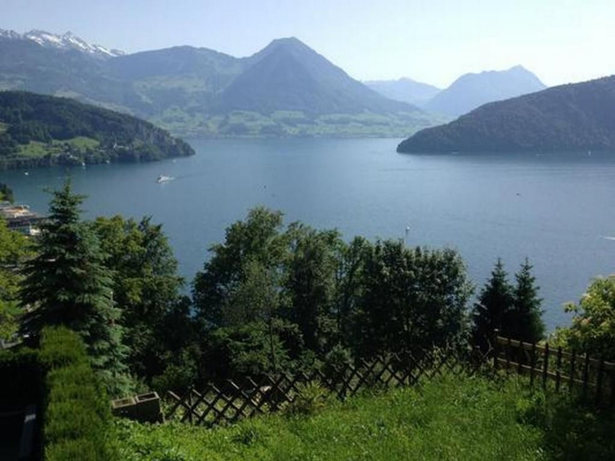 A lake surrounded by mountains with a wooden fence in the foreground.