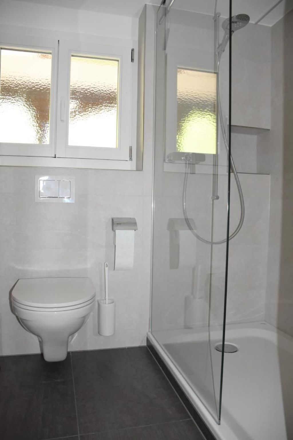 Un baño con inodoro, bidé y ducha con mampara de vidrio.