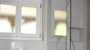 Een badkamer met toilet, een bidet en een douche met glazen wanden.
