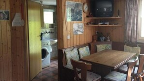 Una cucina funzionale con lavatrice, un tavolo da pranzo con sedie e una televisione su uno scaffale.