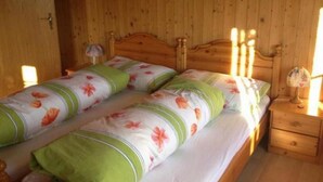 Una stanza in legno con un letto, un comodino e una lampada.