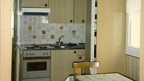 Una cucina compatta con fornello, lavello e schienale piastrellato.