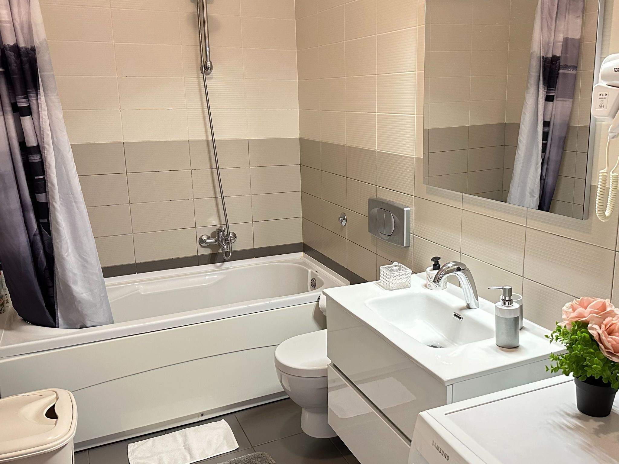 A modern bathroom with a bathtub, toilet, sink, and a mirror.