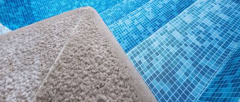 A clear blue pool with a tiled edge and a stone ledge.