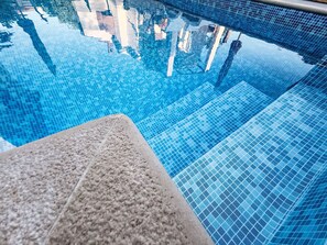 Ein klares, blaues Schwimmbecken mit einer gefliesten Kante und einem Steinvorsprung.