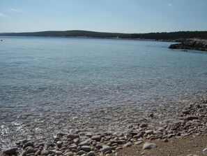 A pebbly beach with clear water and distant hills. - Gemütliches Appartment direkt am Strand by Interhome (Brovinje)