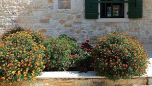 A stone building with a window and shutters, surrounded by flowering bushes. - "Villa Ulika" mit eigenem Pool by Interhome (Rovinj/Kanfanar)