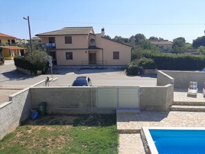 Ein Wohnhaus mit Swimmingpool, einem Auto auf der Auffahrt und einem zweistöckigen Haus mit Ziegeldach.