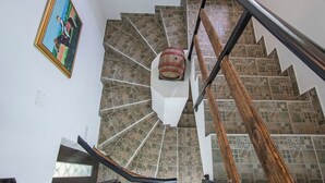 Eine Wendeltreppe mit hölzernem Geländer und einem verzierten Holzfass an der Spitze.
