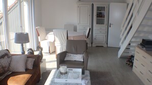 Ein Wohnzimmer mit braunem Sofa, einem Couchtisch und einem Essbereich mit Stuhl und Schrank.