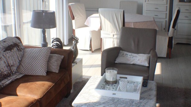Ein Wohnzimmer mit einem braunen Sofa, einem weißen Sessel, einem Marmortisch und einer Lampe.