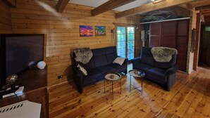 A cozy wooden cabin interior with a sofa set, two side tables, and a television. - Blaues Haus by Interhome (Poddąbie)