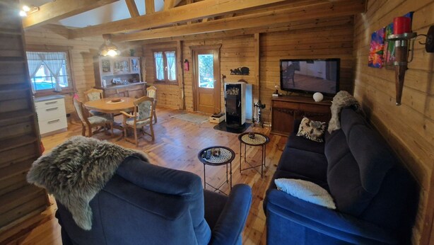A cozy log cabin interior with a dining area, a living room with sofas, a TV, and a fireplace. - Blaues Haus by Interhome (Poddąbie)