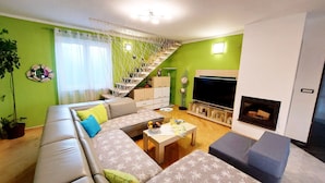 Ein Wohnzimmer mit einer Couch, einem Couchtisch, einem Fernseher und einer Treppe.