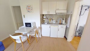 A compact kitchen with white cabinets, a microwave, a sink, and a small dining area with a table and chairs. - Wohnung Lungomare, 300m vom Strand entfernt, Pula by Interhome (Pula)