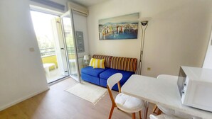 A modern living room with a blue sofa, white chairs, a white table, and a painting on the wall. - Wohnung Lungomare, 300m vom Strand entfernt, Pula by Interhome (Pula)